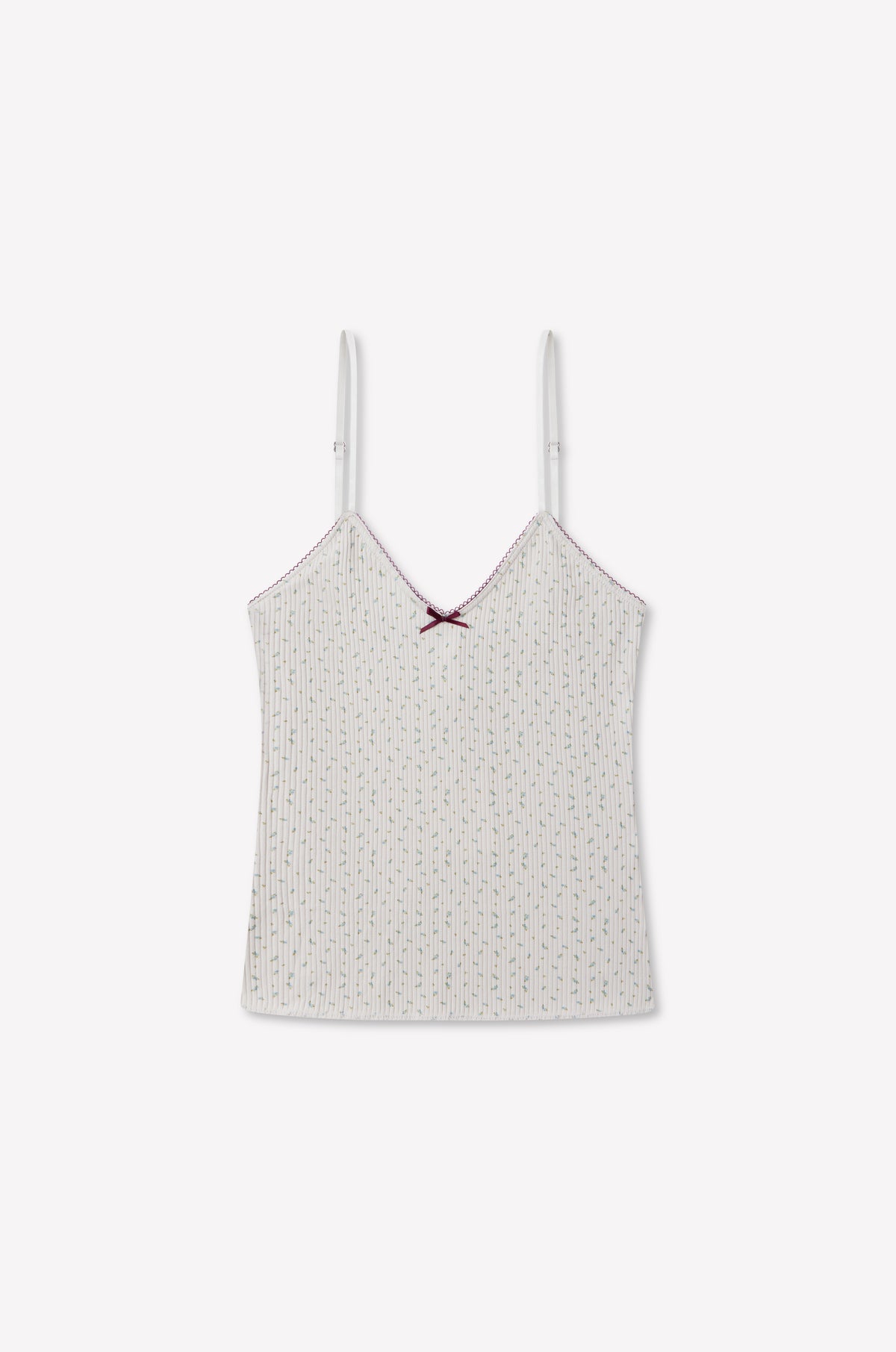 Margot Tank - Blue Floral by 0 features spaghetti straps and a delicate blue floral pattern. A subtle red bow adorns the neckline, while scalloped edging and red stitching on the hem and straps add a charming touch. Made from organic ribbed cotton, this comfortable tank stands out against a plain, light-colored background.