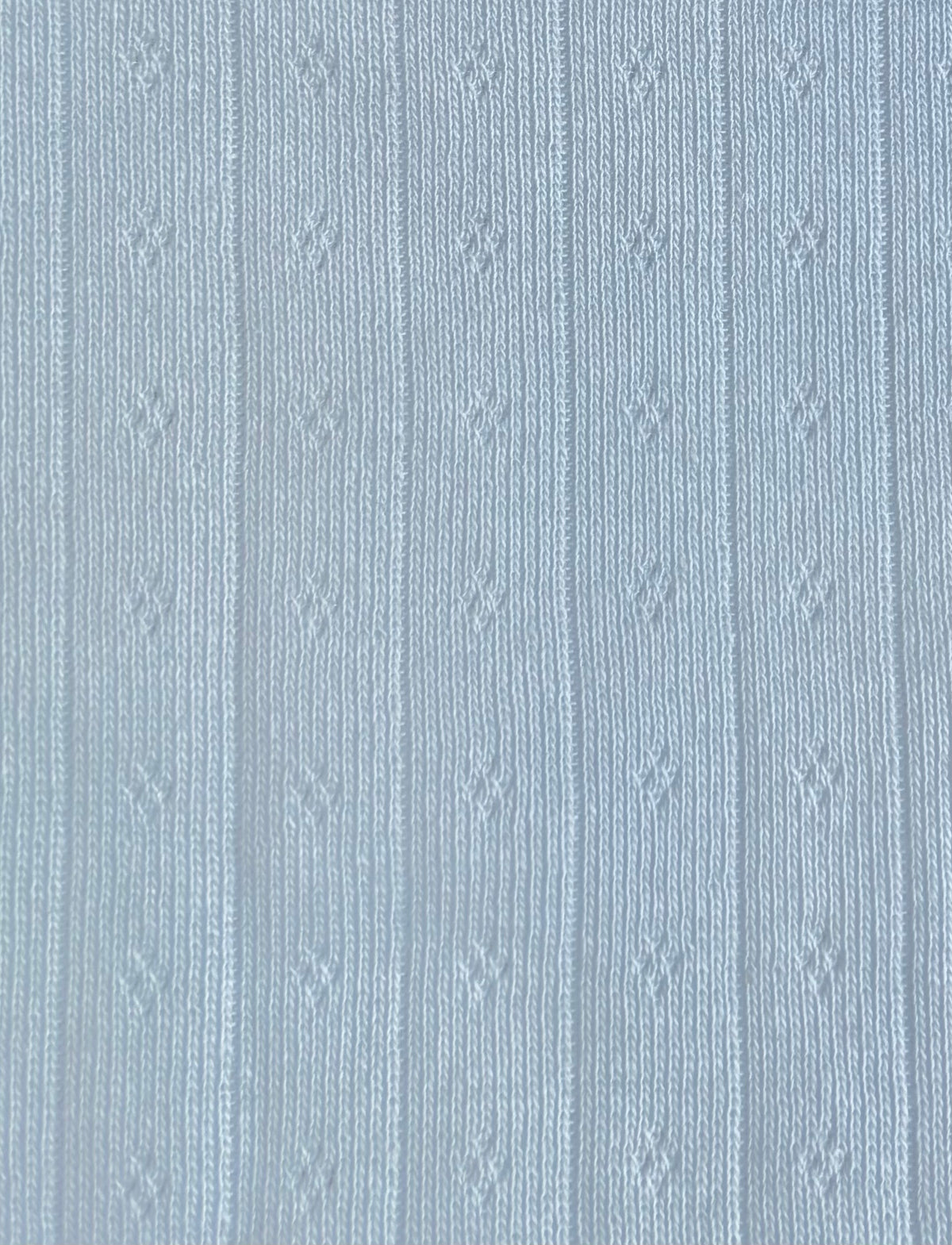 A close-up of the Fern Top - Glacier Blue by Juem, showing the soft glacier blue pointelle knit with its fine openwork detail.