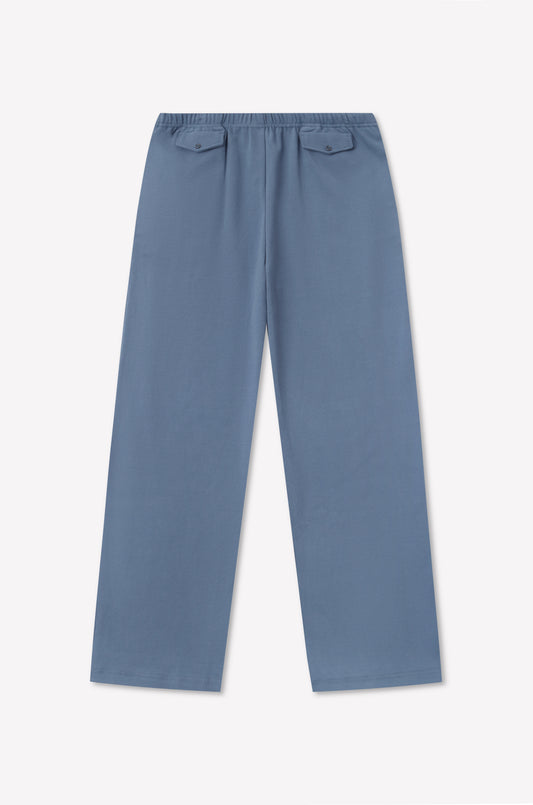 The Vera Track Pant - Sea Blue by 0 features a relaxed fit, an elastic waistband, and two buttoned back pockets, laid flat on a white background.