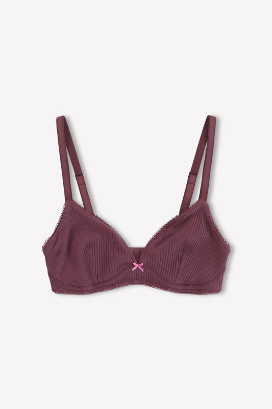 The Sophia Soft Tri - Plum by 0 is a maroon everyday bra with thin straps, ribbed fabric, lace trim, and a pink bow at the center. It offers medium coverage and is shown laid flat on a white background.