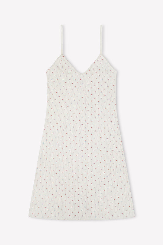 The Lola Mini Dress - Flora is a sleeveless white mini dress with thin straps and a delicate pink floral pattern, shown on a plain white background—ideal for breezy summer days.