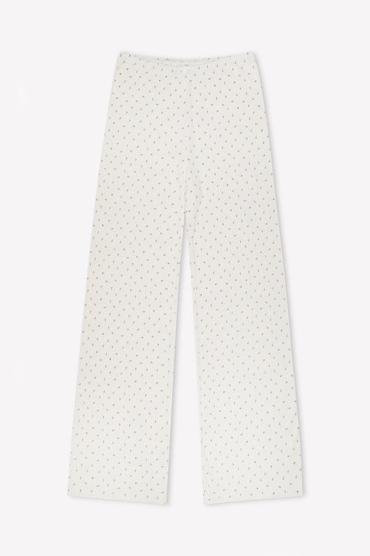 The Maya Pant - Flora features wide-leg white pajama pants with a small red dotted pattern, made from organic cotton for comfort, shown laid flat on a white background.