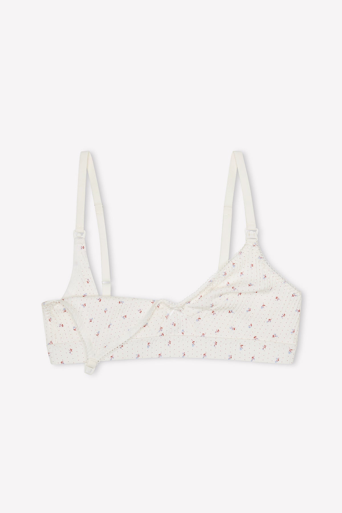 The Paloma Maternity Bra - Flora features a white organic cotton fabric with a small pink floral print, adjustable straps, and a wrap-style front for soft, comfortable everyday wear.